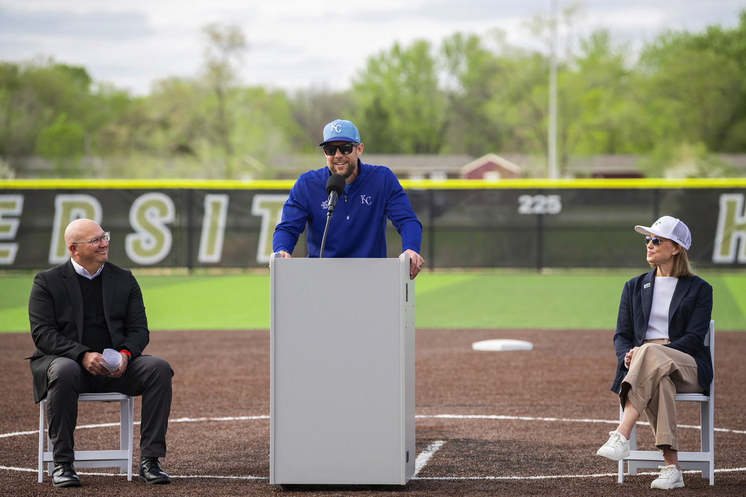 Charlie Colon, nonprofit board president of the Sandhills Global Youth Complex, and Lincoln Mayor Leirion Gaylor Baird listen as former Major League Baseball All Star Alex Gordon addresses the grand opening ceremony at the complex.