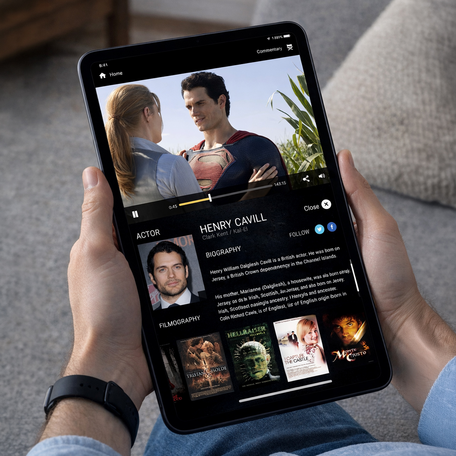 Person holding a tablet showing a video of Superman and Lois Lane with actor Henry Cavill's biography and filmography.