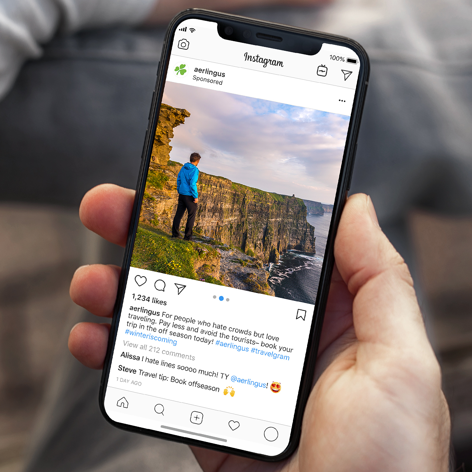 Instagram post from Aer Lingus showing a person in a blue jacket standing on a green cliff overlooking the sea and rocky coastline.