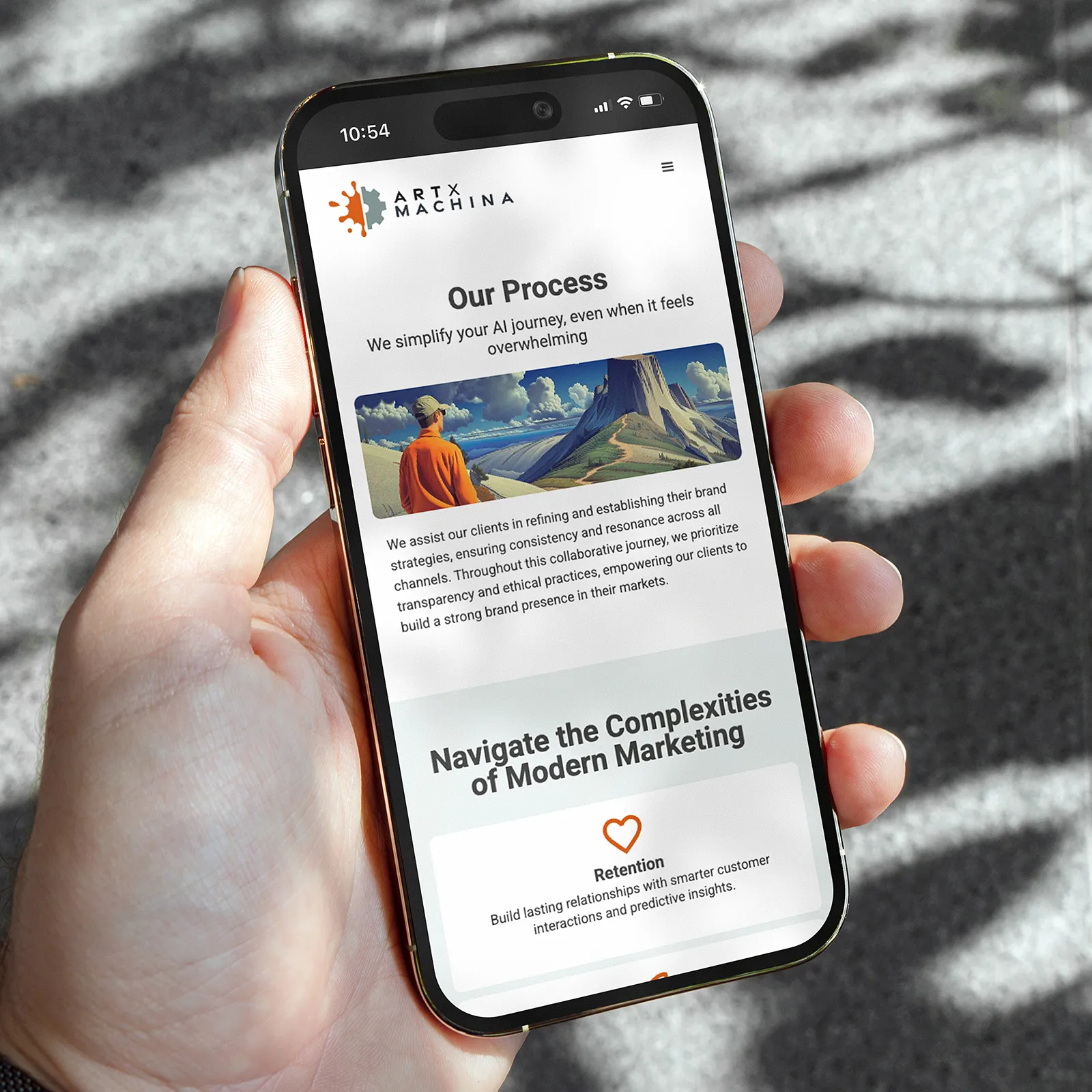 Hand holding smartphone displaying Art X Machina webpage titled 'Our Process' explaining AI journey simplification and modern marketing strategies.