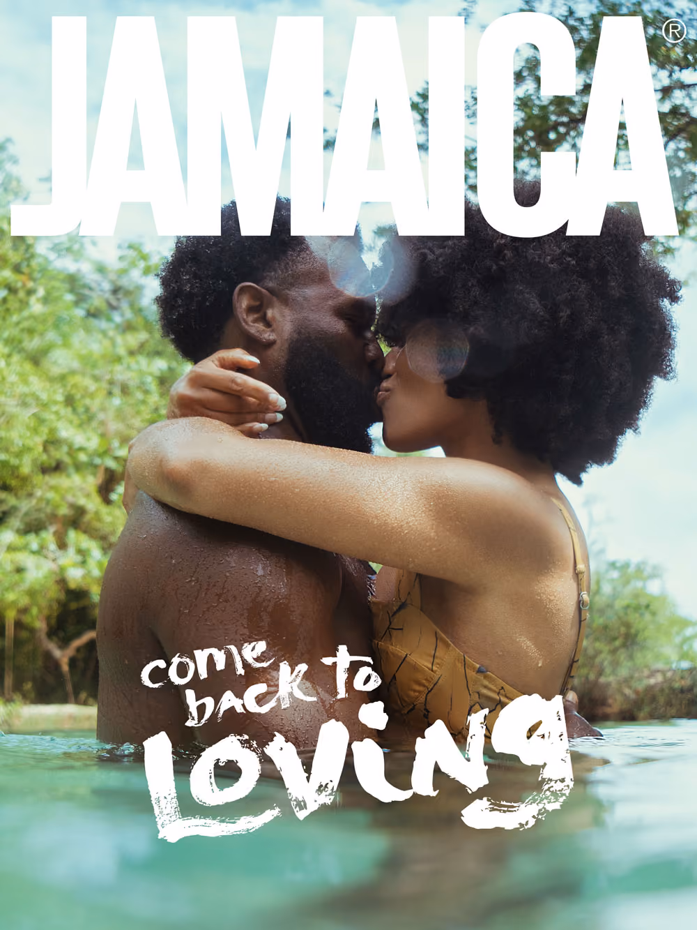 Couple embracing and kissing in water with lush greenery background and text Jamaica come back to loving.