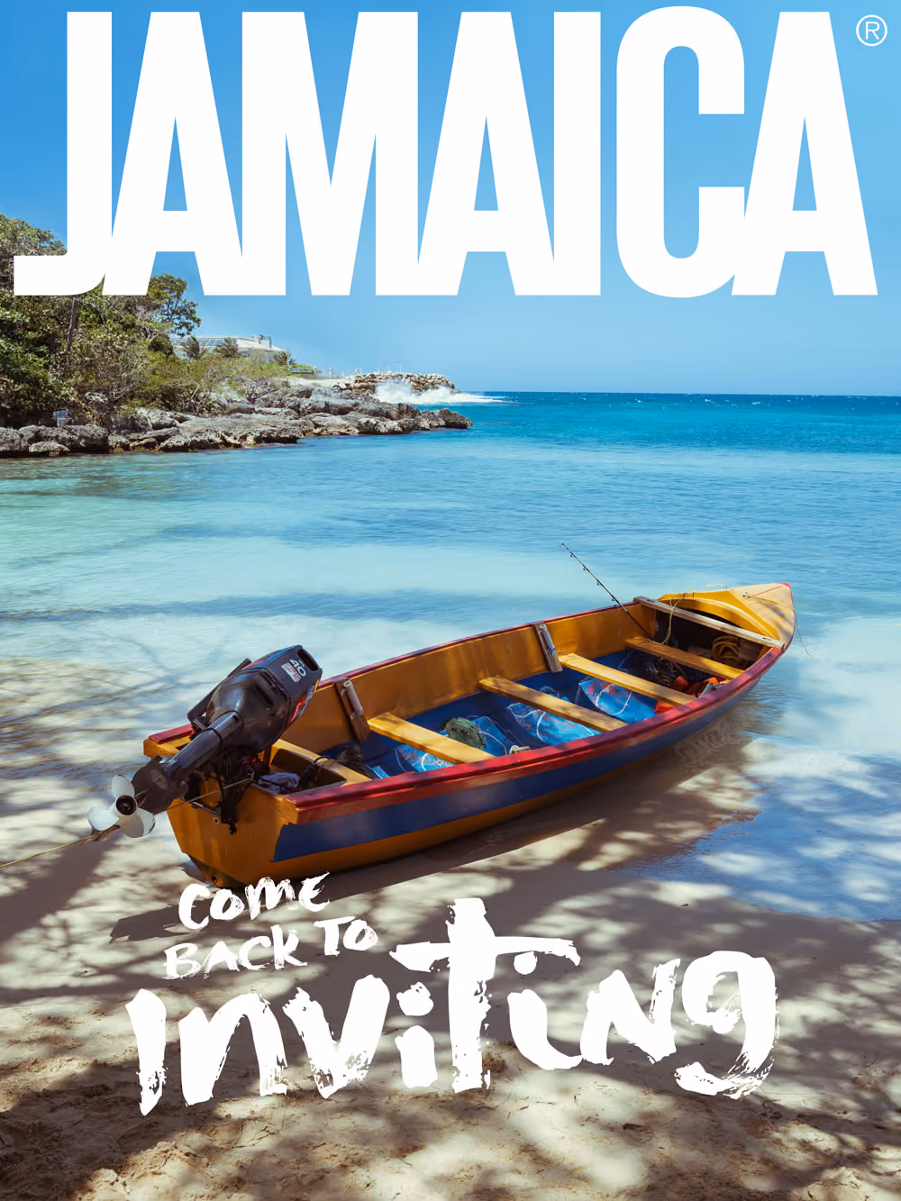 Wooden motorboat on clear blue water near rocky shore under a bright blue sky in Jamaica.