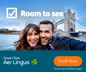 Smiling couple taking selfie near Tower Bridge with Aer Lingus ad saying Room to see and Book Now.