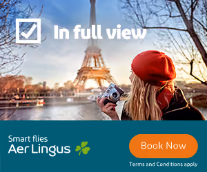 Woman in red beret holding camera near Eiffel Tower with Aer Lingus ad and Book Now button.