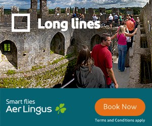 People standing in a long line on a stone walkway at a historic site with cloudy blue sky above, with overlay text 'Long lines,' and an Aer Lingus advertisement below with 'Smart flies Aer Lingus' and a 'Book Now' button.