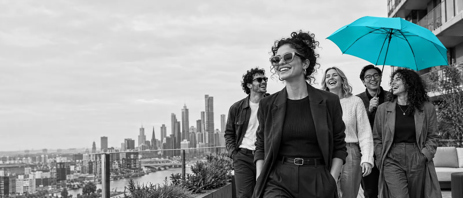 A Strata Plan manager walks with a team of specialists on a Melbourne rooftop, one holding a blue umbrella.