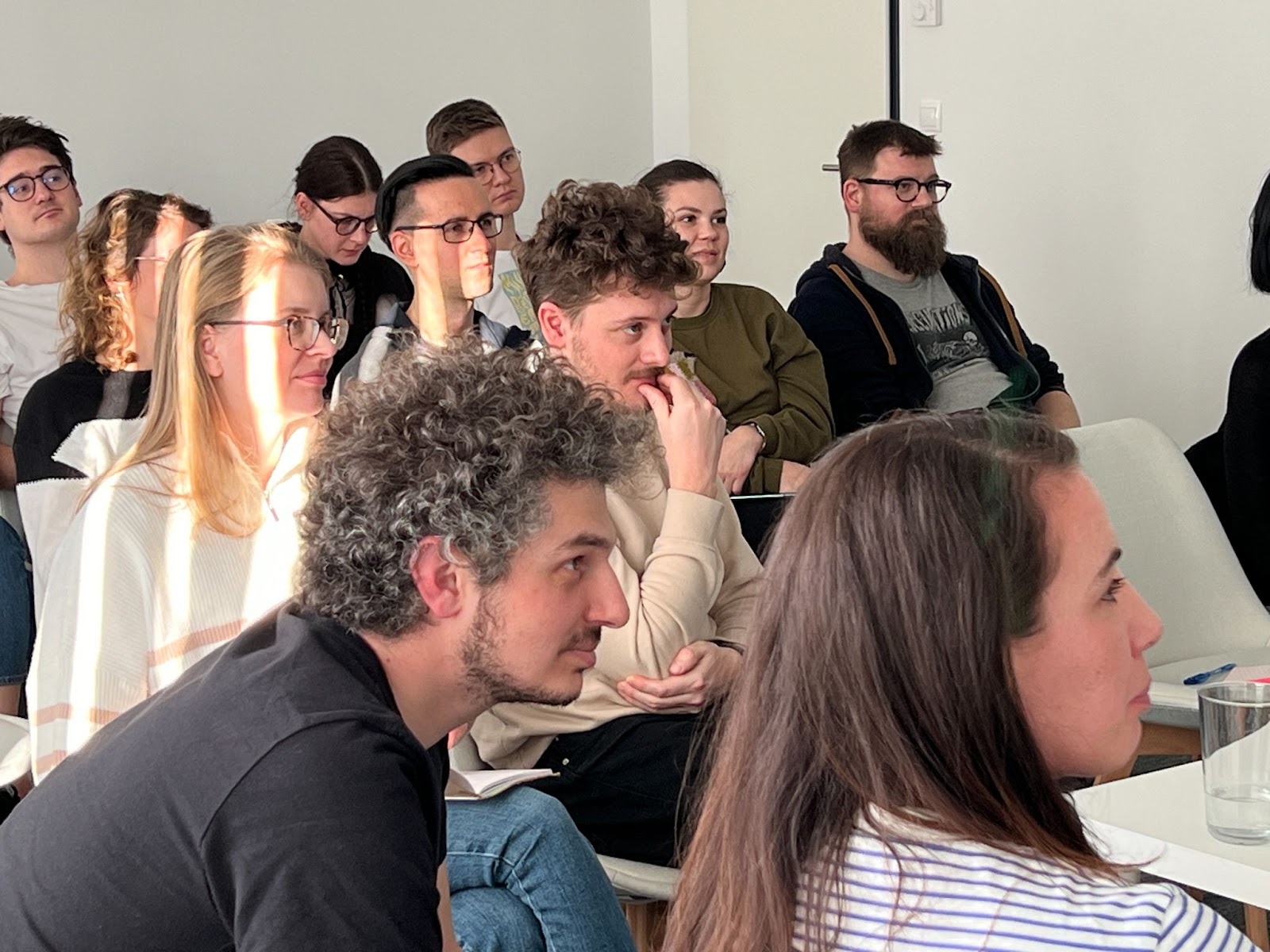 The majority of the audience look surprised or bemused: an interesting fact may have been presented. One audience member seems skeptical. A few people have zoned out.