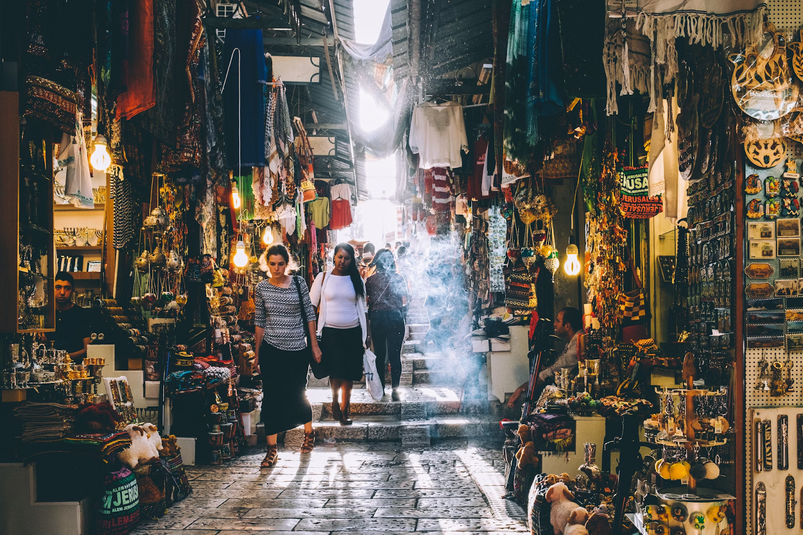 People walking on a street market with shops having all types of objects.
