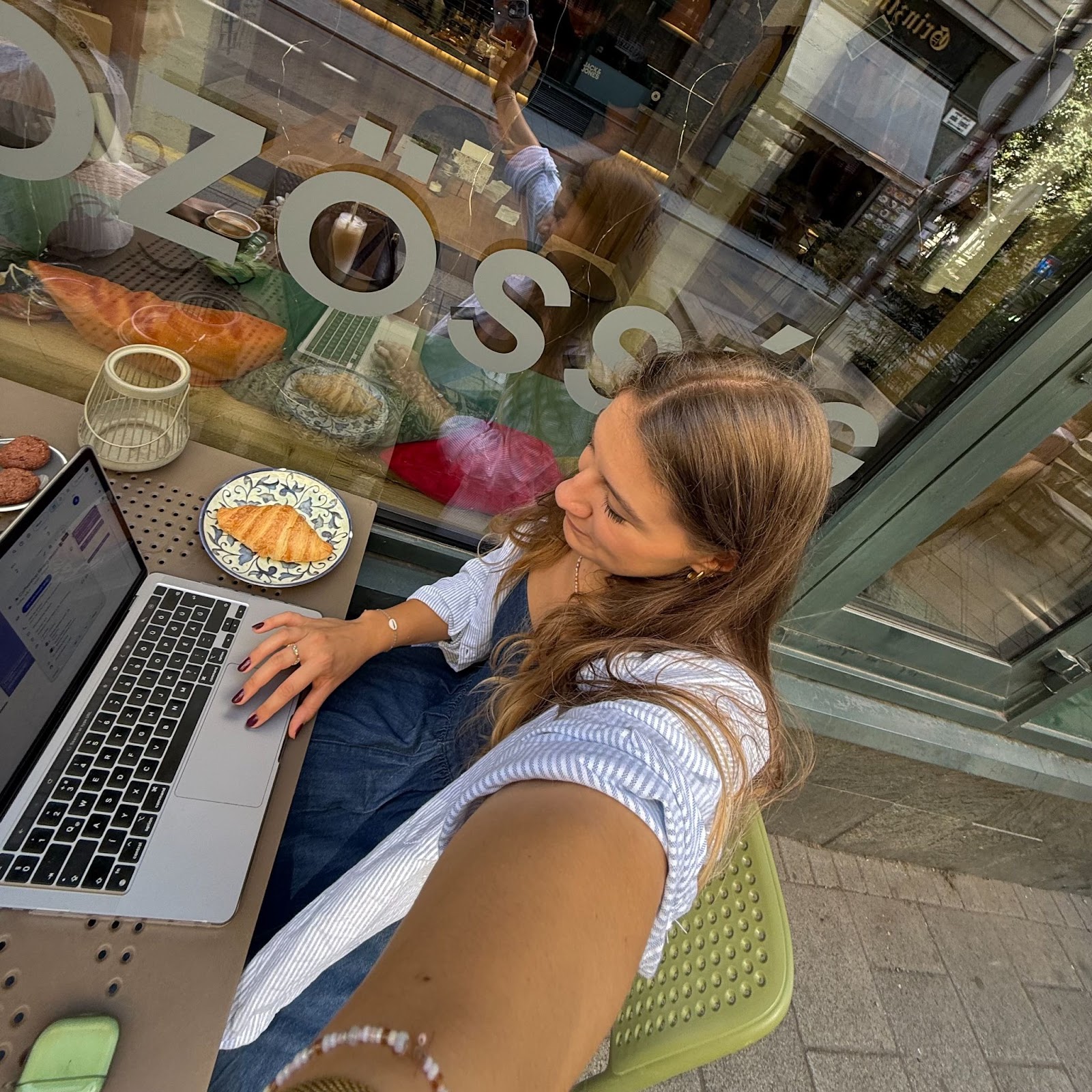 A selfie of a marketer working in a coffeeshop, typing on her laptop