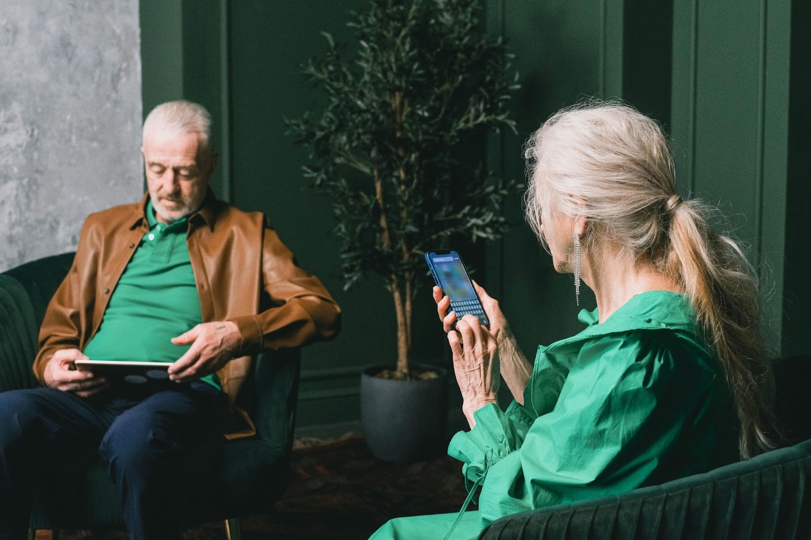 An elderly couple using a tablet and a phone, respectively