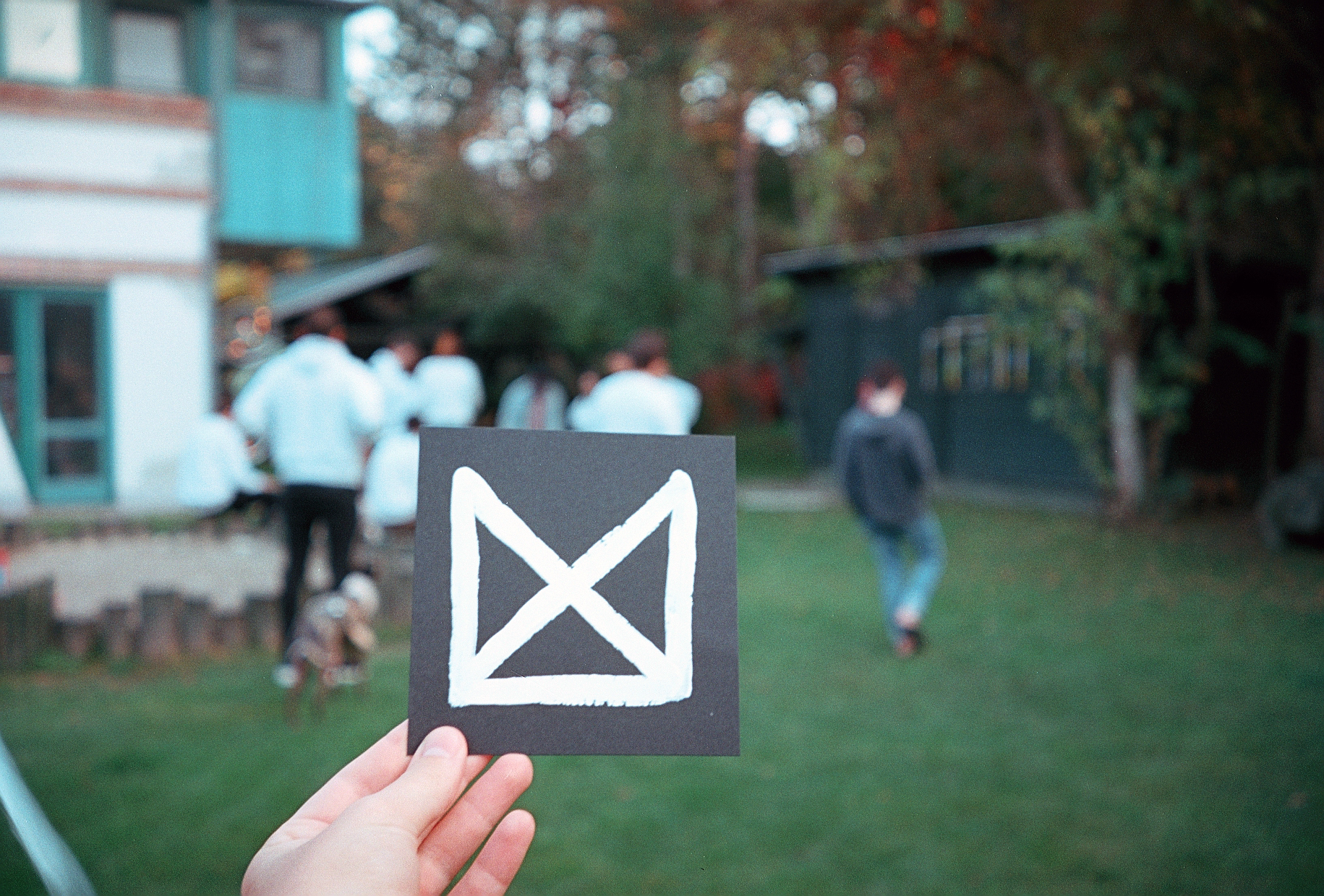 Photo of a hand-painted UX studio logo, held up at a retreat location, with the team blurred in the background