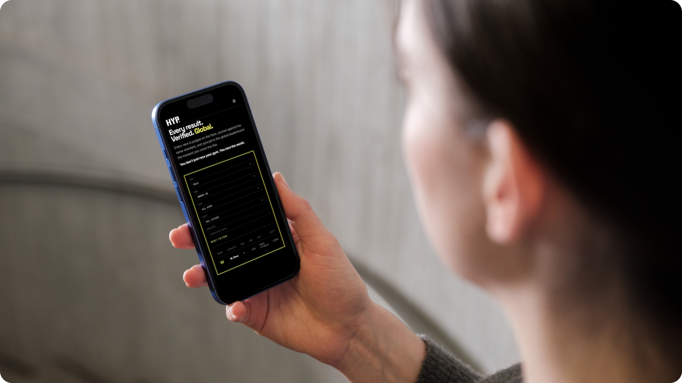 A person looks at their phone, which is displaying the HYP fitness-racing apps input form for registration