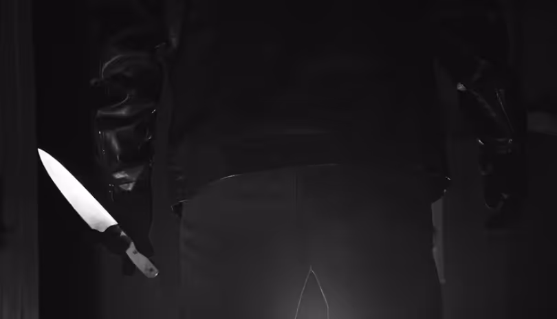 Ein Schwarz-Weiß-Foto einer bedrohlichen Person in einer Lederjacke, die von hinten gesehen wird und ein scharfes Messer hält, symbolisiert die Bedrohung der Website-Performance durch schlechte Programmierung und technische Schulden. upgreight, die Webflow Agentur Südtirol, eliminiert diese Performance-Killer, um High-End-Seiten zu sichern.