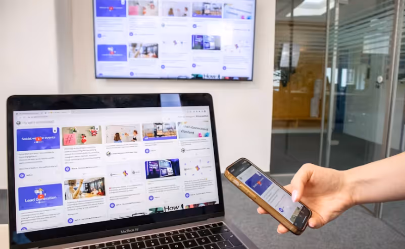 Eine Social-Media-Wall wird nahtlos auf drei Screens dargestellt: Einem TV-Monitor im Hintergrund, einem MacBook Air und einem Smartphone in der Hand.