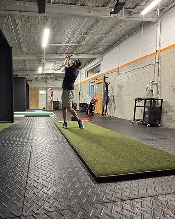 Golfer swinging in a warehouse bay