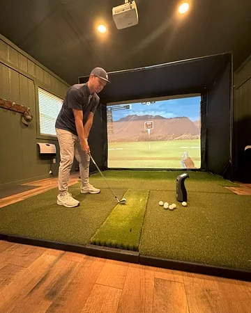 Golfer at the sim inside the shed