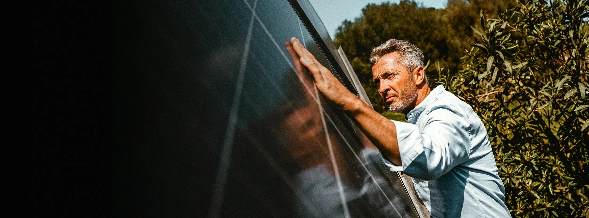 Person steht an einer Solaranlage, legt seine Hand auf und betrachtet die Oberfläche genau