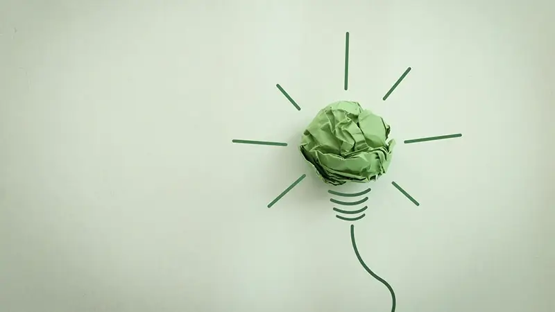 Das Bild mit einer grünen Glühbirne symbolisiert neues Wissen zum Investitionsabzugsbetrag (IAB) für Photovoltaikanlagen.