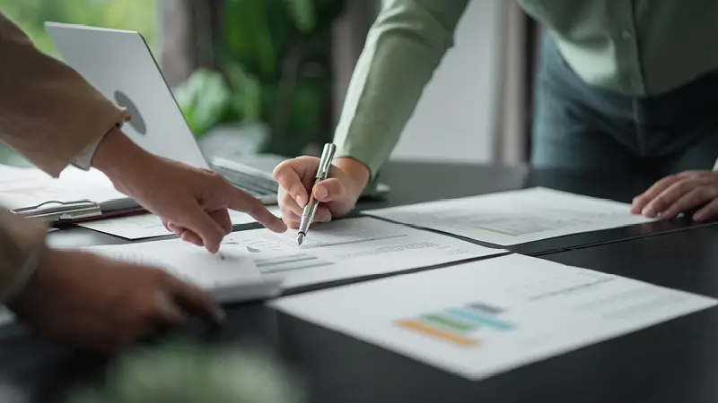 Das Bild zeigt zwei Personen, die sich die Kalkulation für die Kosten eines Freiflächen-Solarparks anschauen.