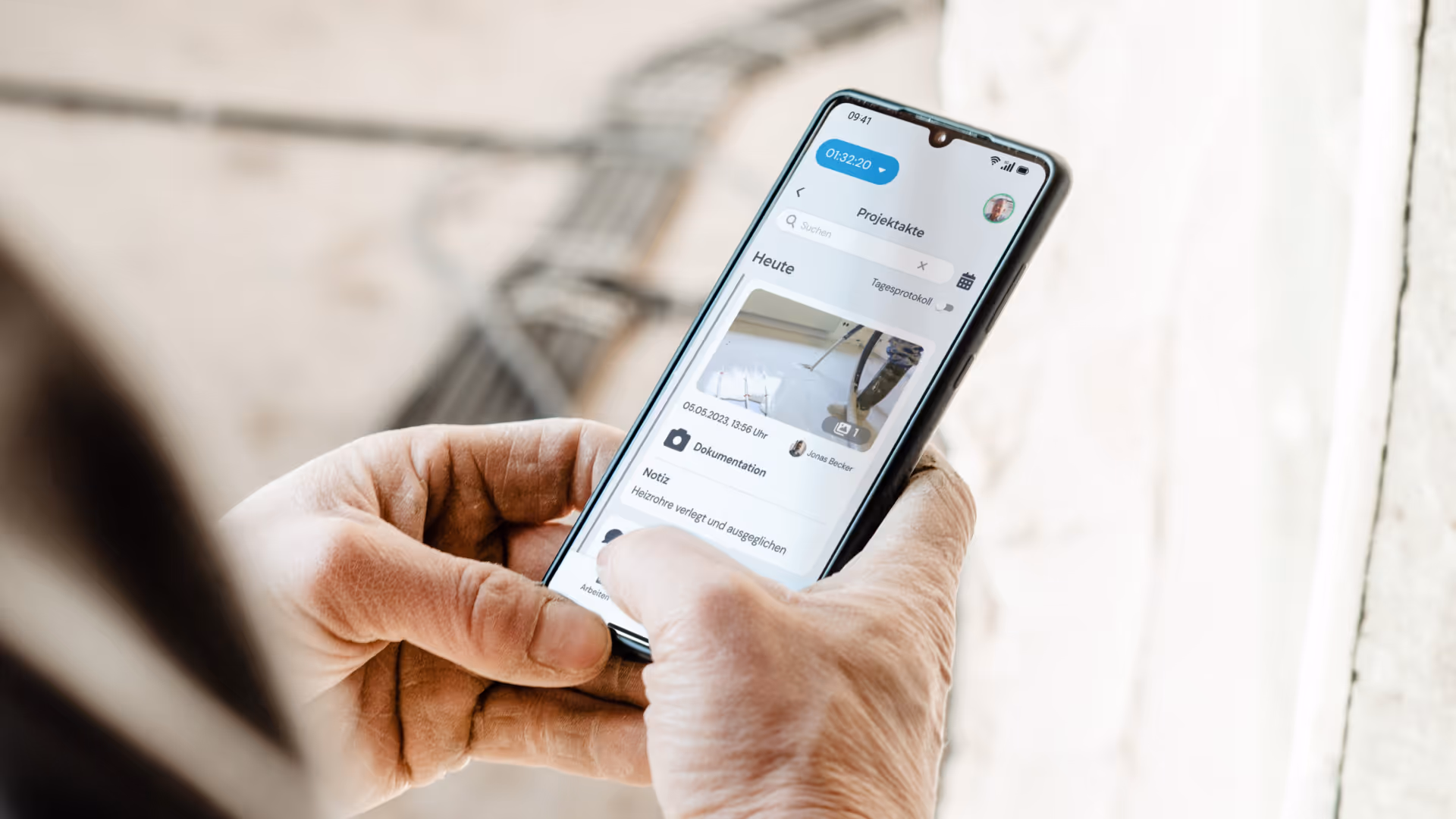 Handwerker hält Smartphone mit geöffneter clockin App und dokumentiert Baustelle digital in der Projektakte