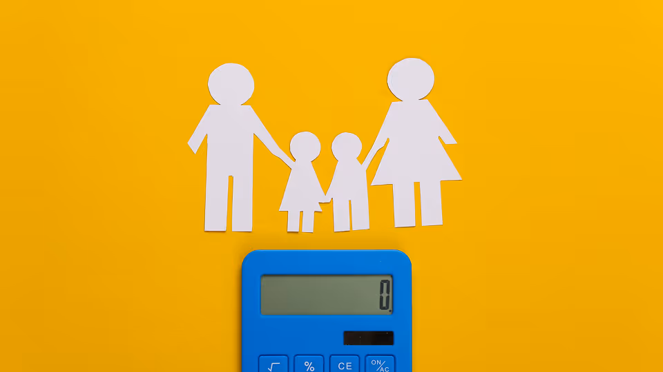  Eine blaue Taschenrechner liegt auf einem gelben Hintergrund. Oberhalb des Taschenrechners sind weiße Papierfiguren einer Familie zu sehen, bestehend aus zwei Erwachsenen und zwei Kindern, die sich an den Händen halten.