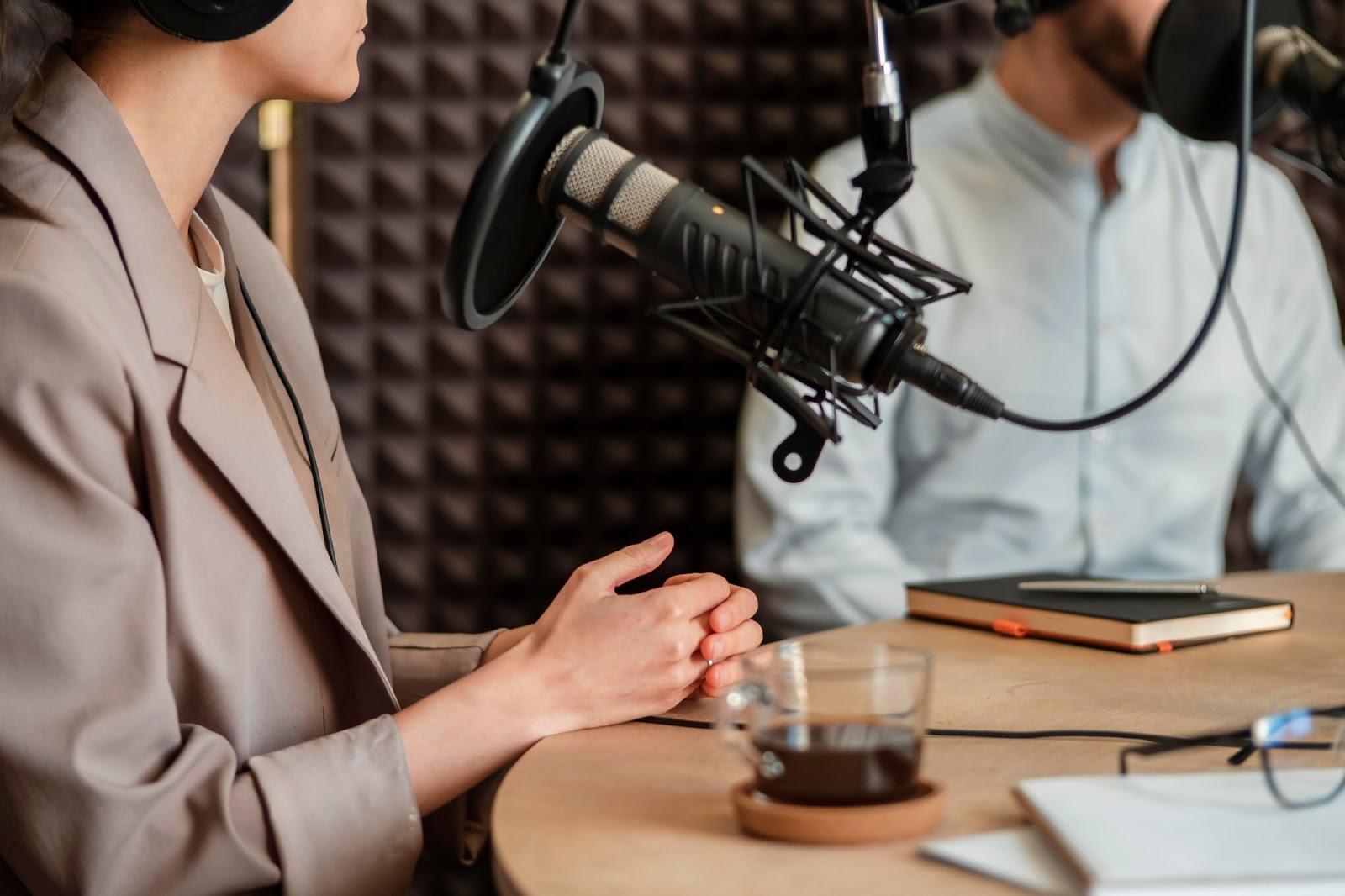 Two people recording a podcast in a professional studio with microphones