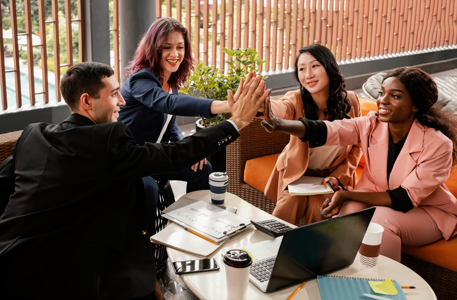 Four co-workers high fiving