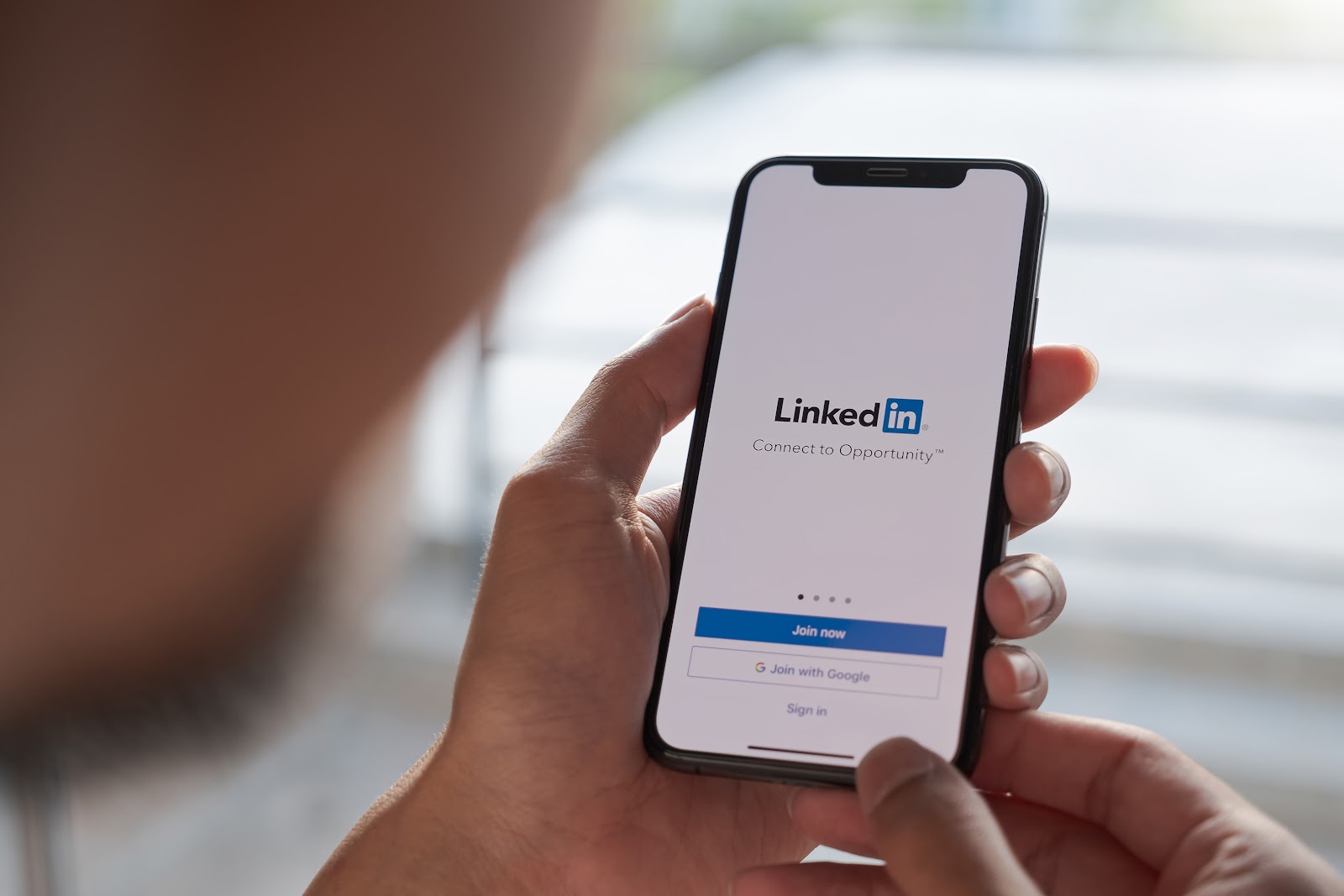 A women holds smartphone with LinkedIn application on the screen