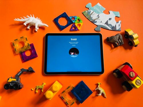 Toddlr's Screen Lock opened on a tablet device surrounded by physical toys