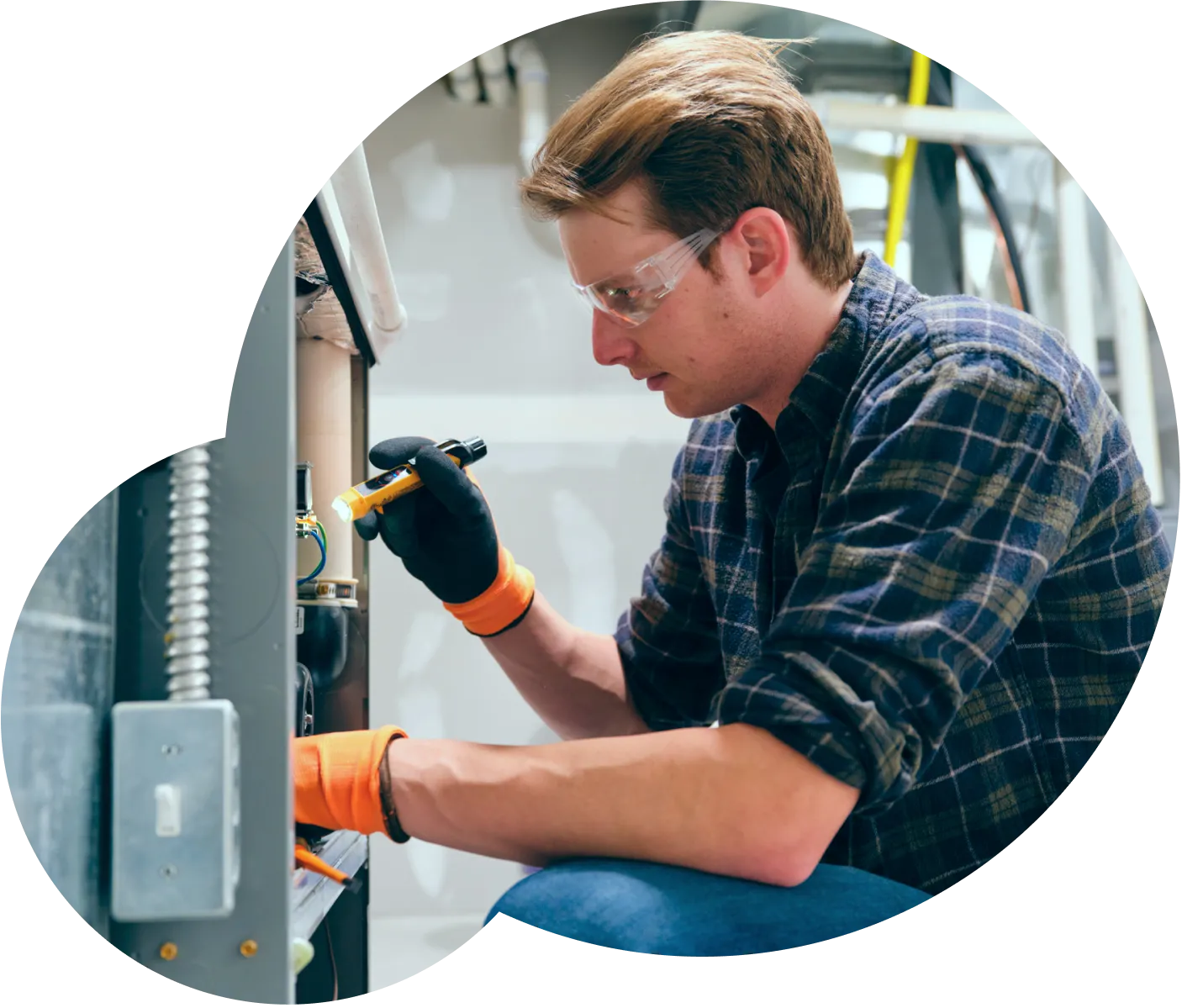 A young man crouched near an AC unit, performing an inspection on the interior of the unit.