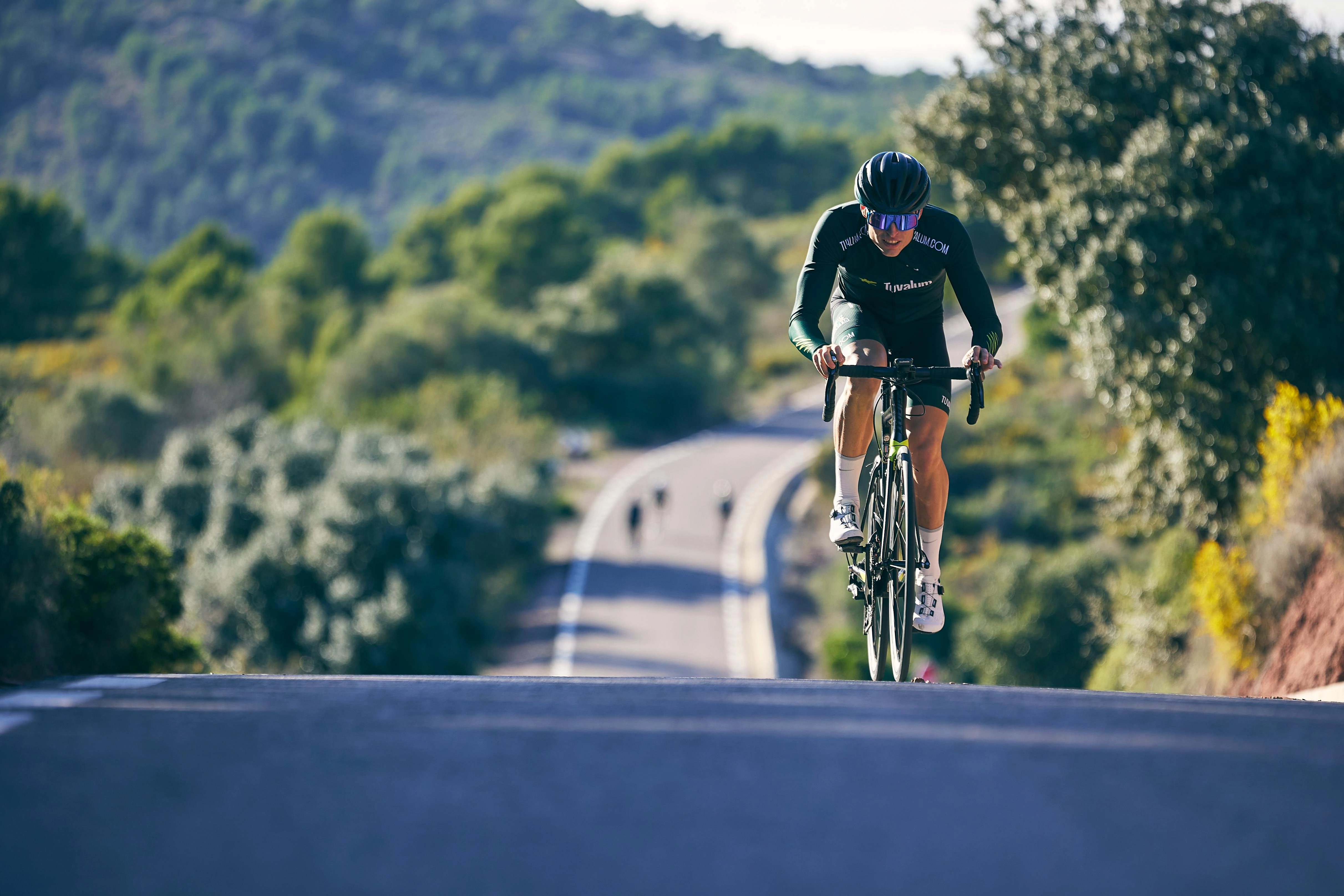 A close up of a person riding a bike over a hill