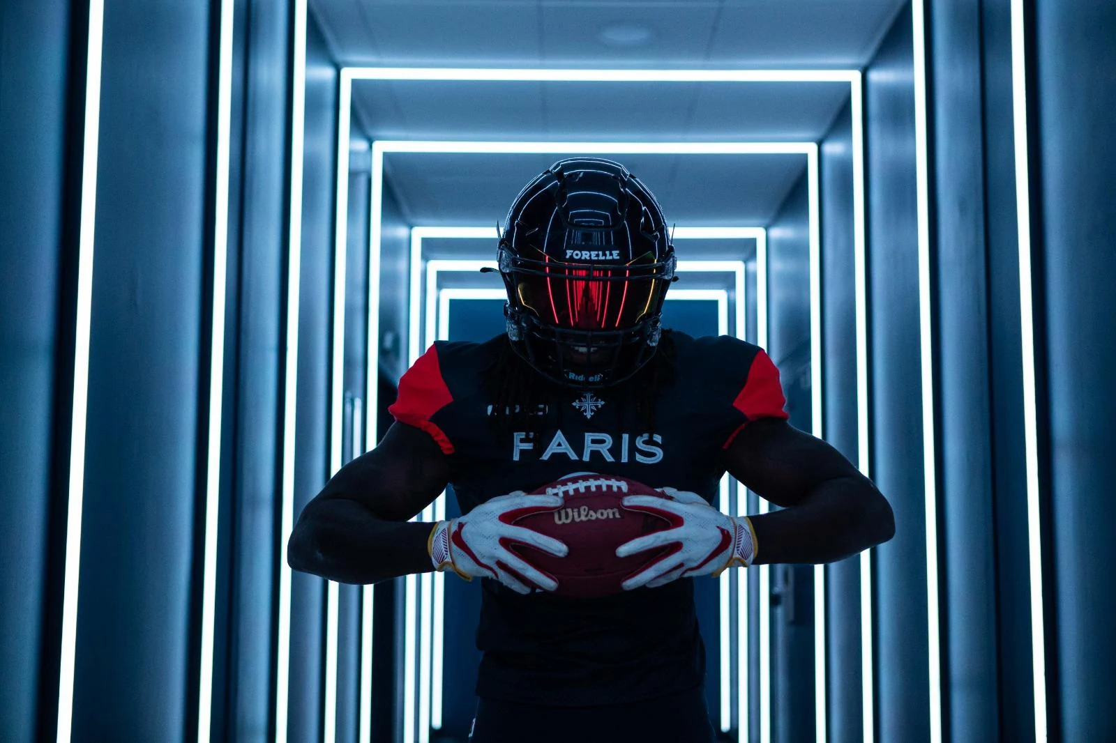 A helmeted Paris Musketeers player holds a football in a tunnel of lights.