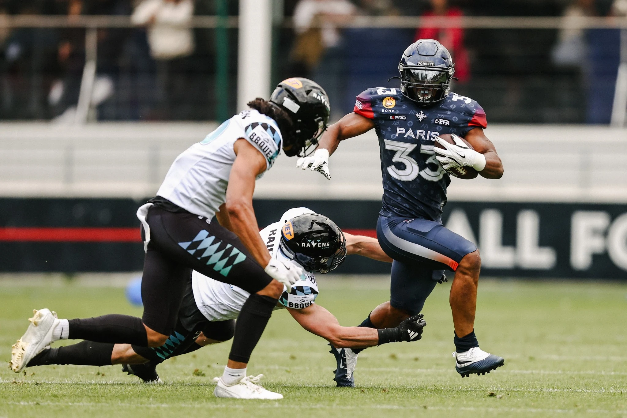 A Paris Musketeers running back breaks through a tackle.