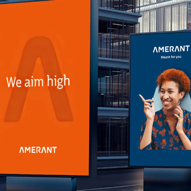 Amerant bank outdoor ads showing the message ‘We aim high’ and a smiling person on a blue billboard