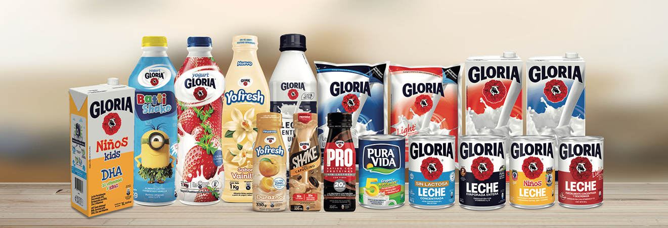 Variety of Gloria dairy products including milk cartons, yogurt bottles, shake bottles, and condensed milk cans displayed in a row on a wooden surface.