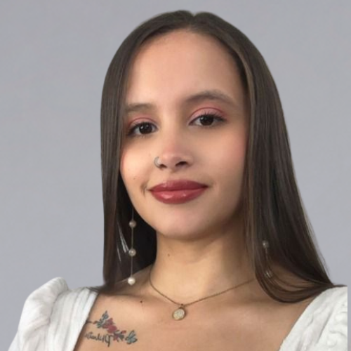Young woman with long straight hair, wearing a white top, pearl drop earrings, and a necklace with a circular pendant.