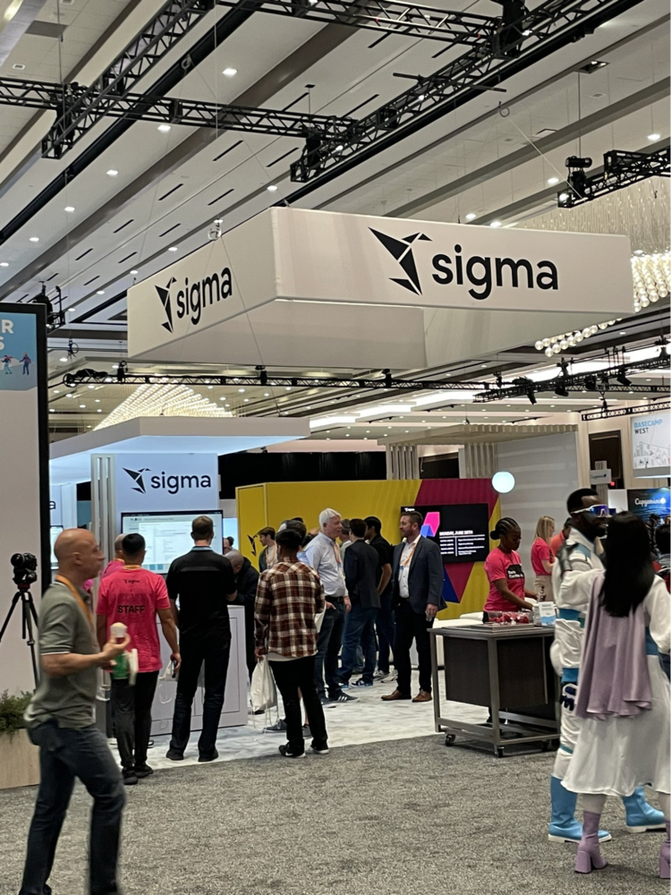 A group of people are standing in front of a Sigma sign.