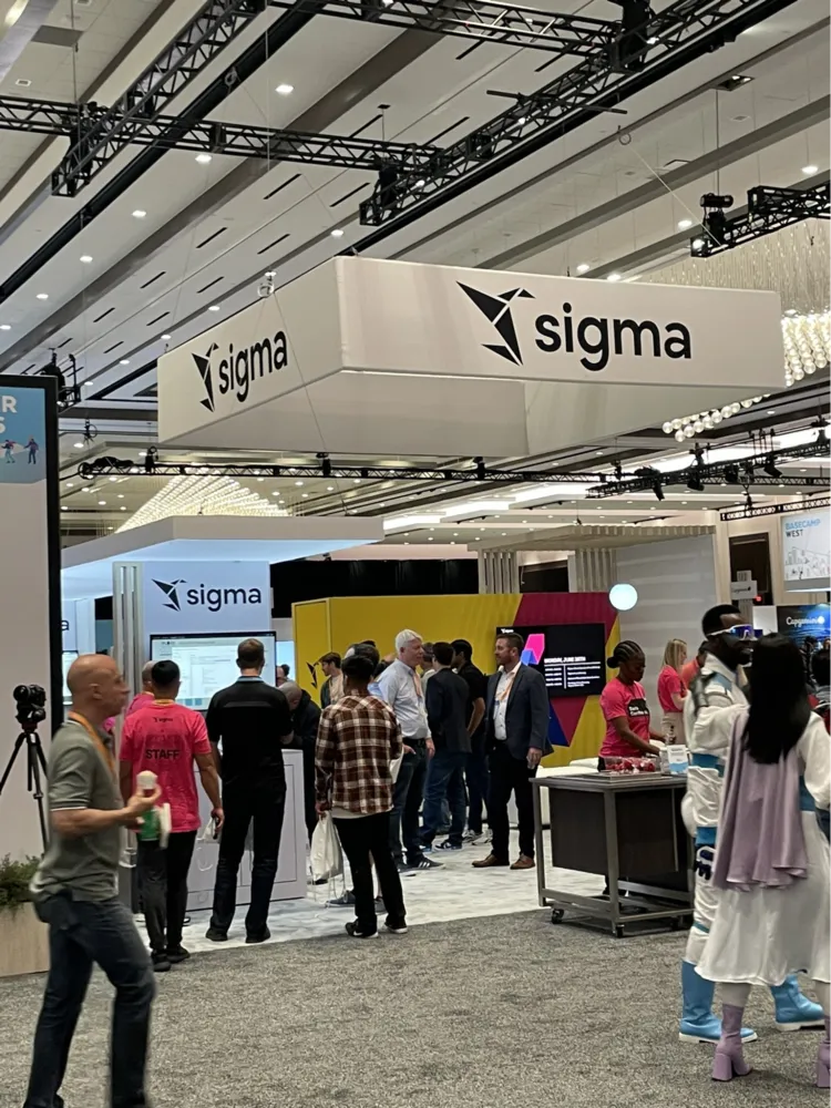 A group of people are standing in front of a Sigma sign.