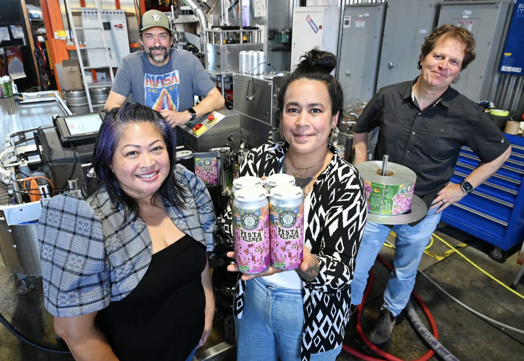 Festival vice chair Mary Medina, artist Niki Toney and Mare Island Brewing's founders with the first Pista Pilsner cans on the canning line