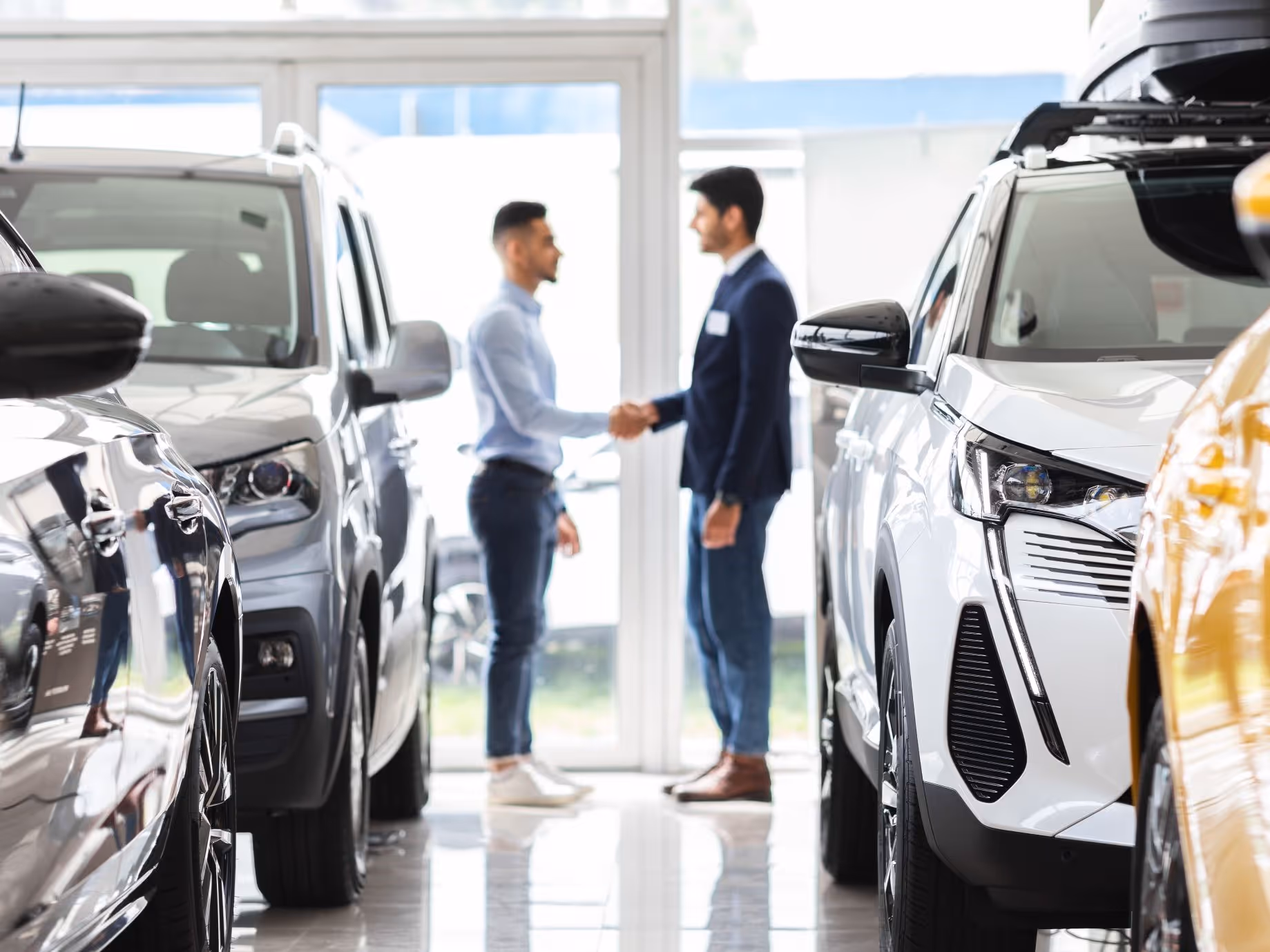 Mann mit Kaffee lehnt an E-Auto und schaut aufs Smartphone