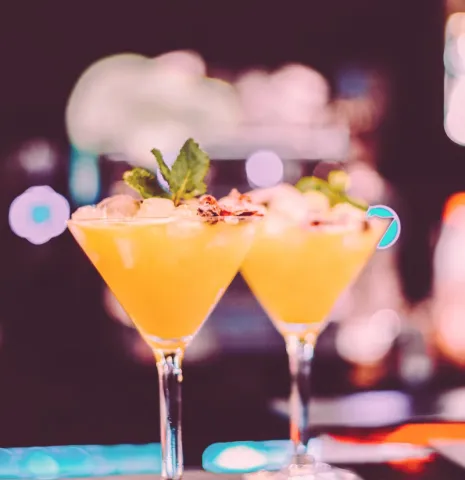 Two yellow cocktails standing on a bar counter