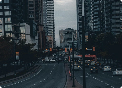 A cityscape view featuring three uniquely shaped high-rise buildings under a partly cloudy sky, with roads and other buildings around.