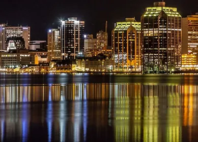 Night view of a city's illuminated skyline reflecting off calm waterfront waters.