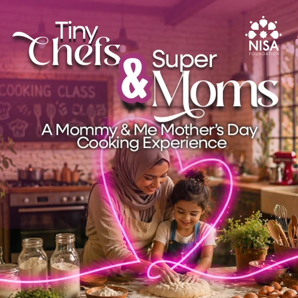 Mother wearing hijab and young daughter smiling while kneading dough together in a kitchen decorated for a Mother's Day cooking experience.