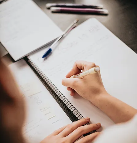 Person writing notes while determining Zakat eligibility and financial assistance.