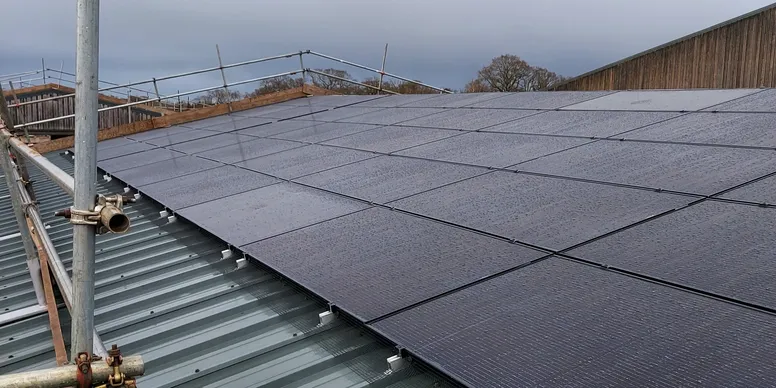 A picture consisting of solar panels on a roof of a commercial building