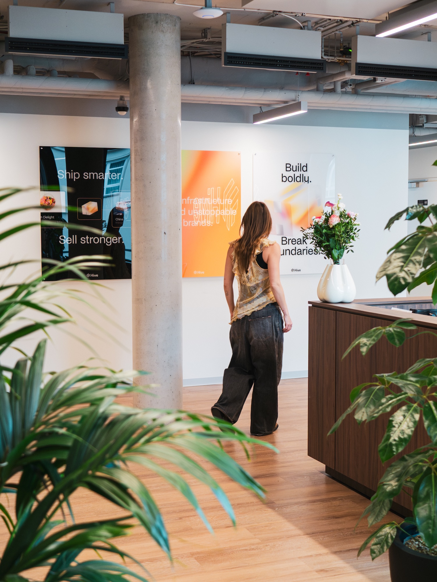 Hive team member walking past branded wall posters and plants in the Berlin office