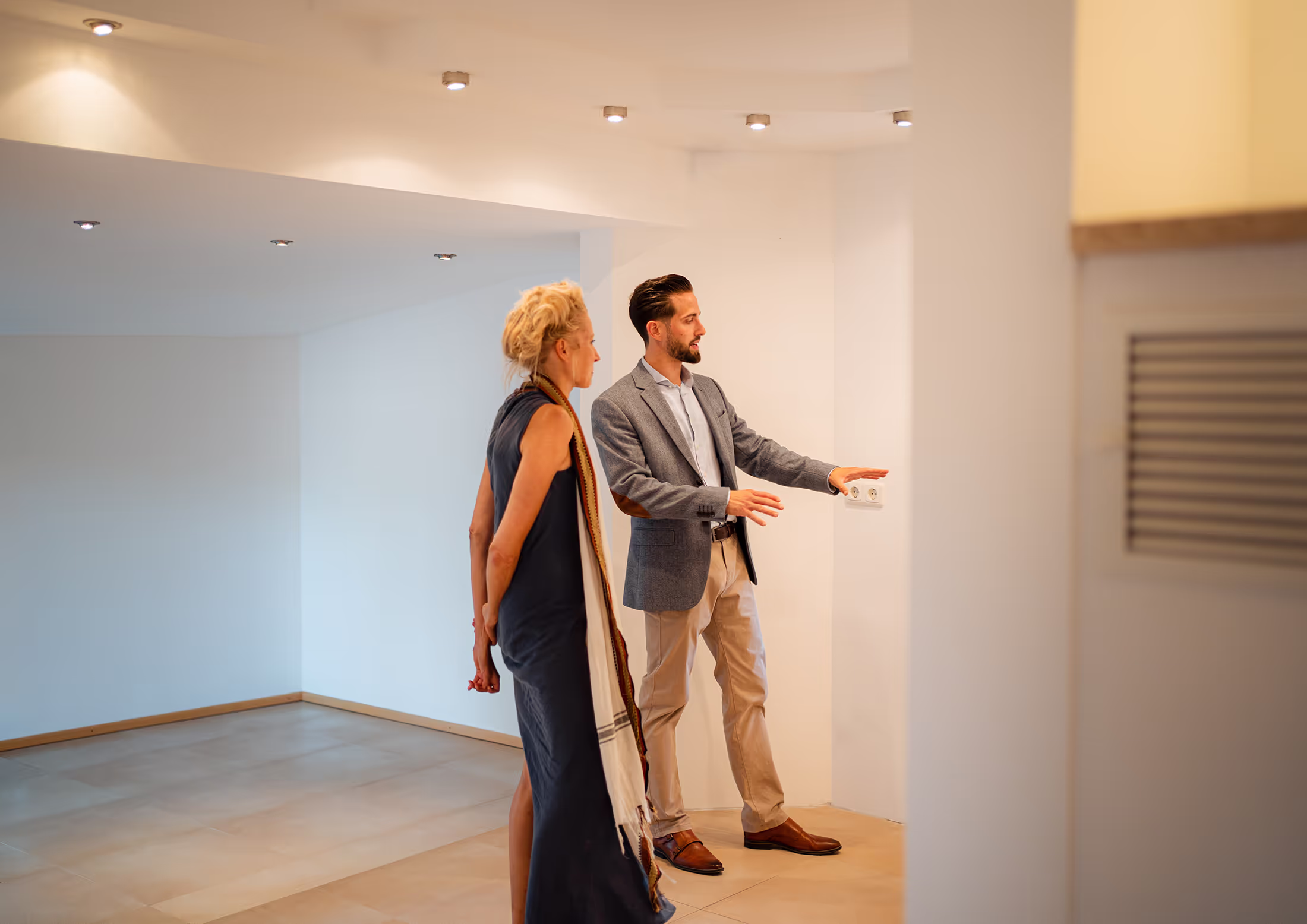 Teleskop Immobilien München – Makler zeigt Kundin eine helle Wohnung.
