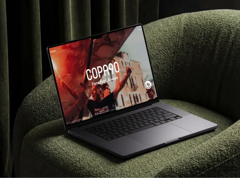 Copa90 website homepage hero section on a laptop mockup, showing the 'Fans First. Always' tagline over a football fan crowd image, designed and built by Code & Wander