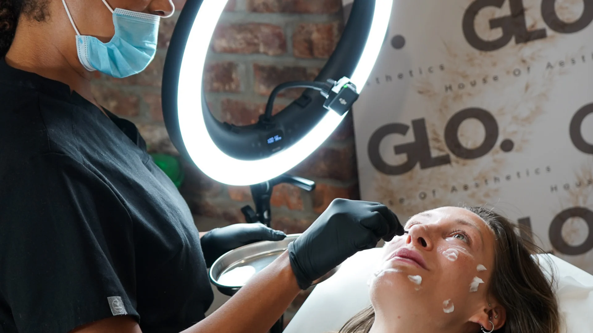 Rosie from GLO applying a soothing treatment product during a client’s skin reset, supported by professional lighting in the Newquay clinic.